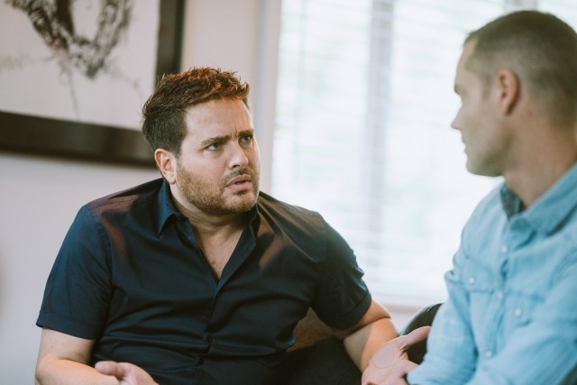 Two men talking on a couch
