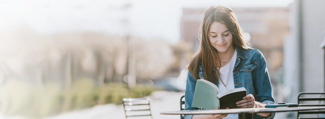 A young girl reads a book outdoors