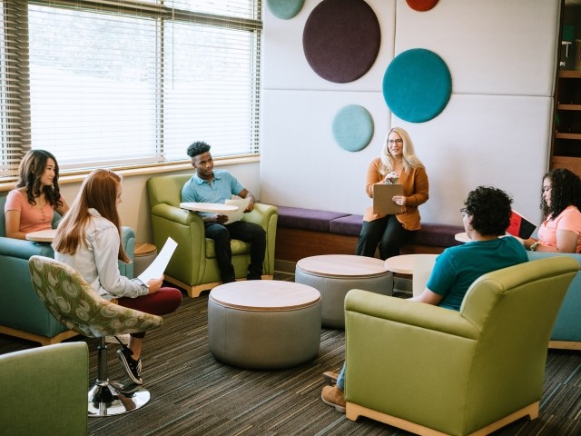A group of adolescent patients works with a therapist in a group environment