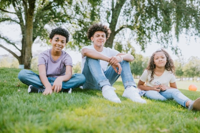 A group of children sit outdoors in a park