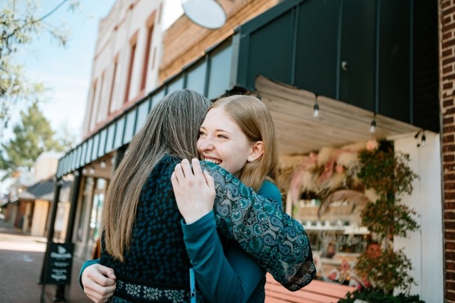 An alumni and her mother hug outdoors