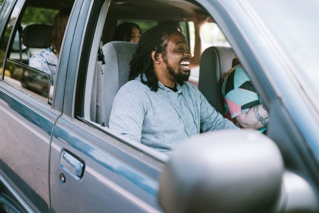 A man rides in a car happy and smiling