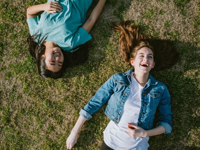 Two young women lay in the grass
