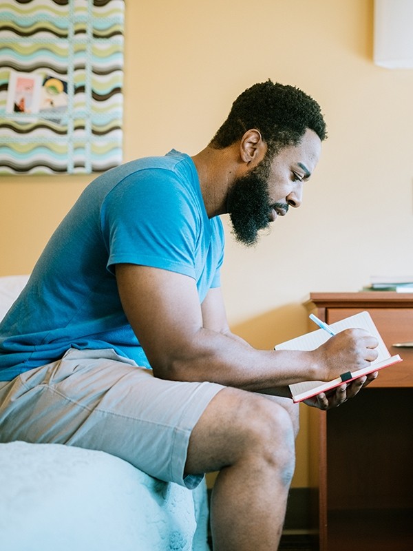 A man writes in a journal in residential care