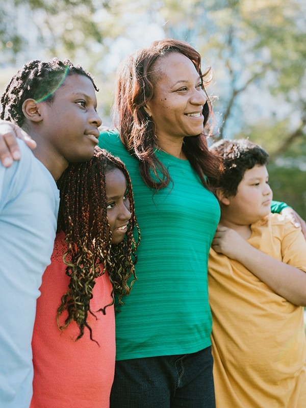 A mother and her children standing outdoors in a park