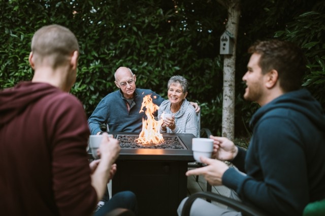 extended family enjoys a fire outdoors after Thanksgiving meal